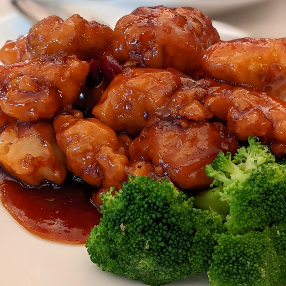 Close-up of Mainland China Bistro's General Tso's chicken with broccoli florets on a white plate.